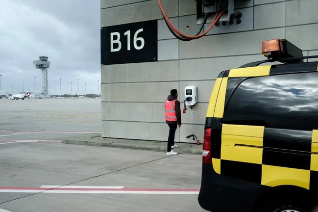 Flughafen BER Berlin Brandenburg: Blick auf das Vorfeld und den Tower im Hintergrund und eine Virta Ladestation