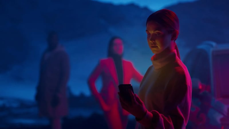 Woman using smartphone while EV charges dusk mountains