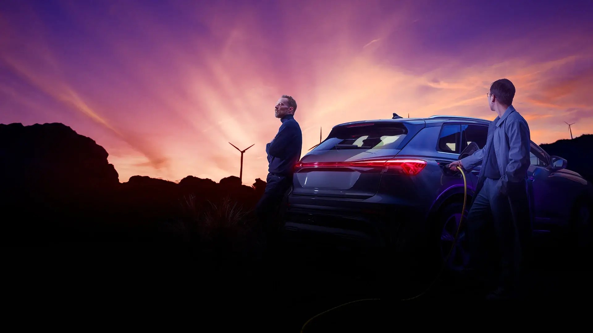 Sunset with EV charging and wind turbines in background