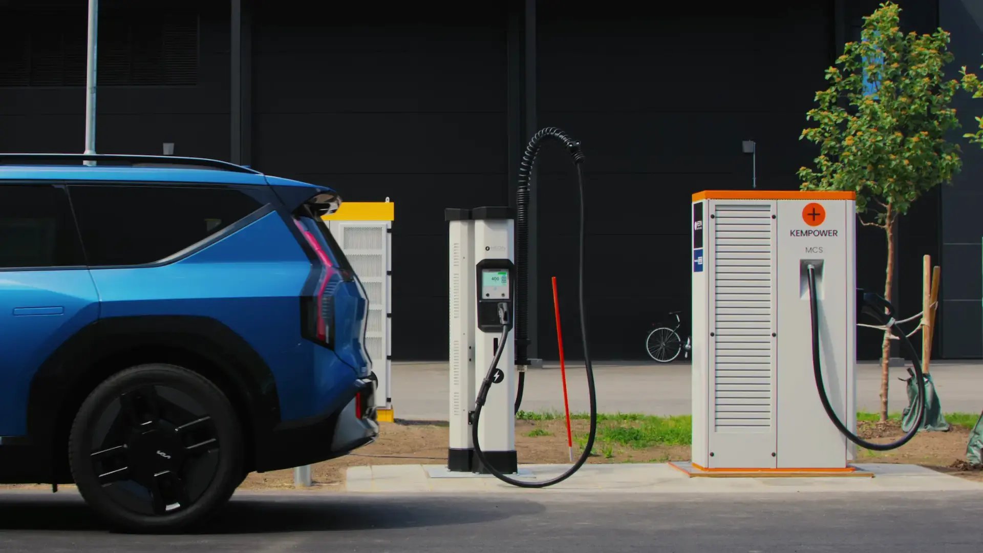 Blue electric SUV in front of a Hedin Supercharger site with Kempower MCS charging units