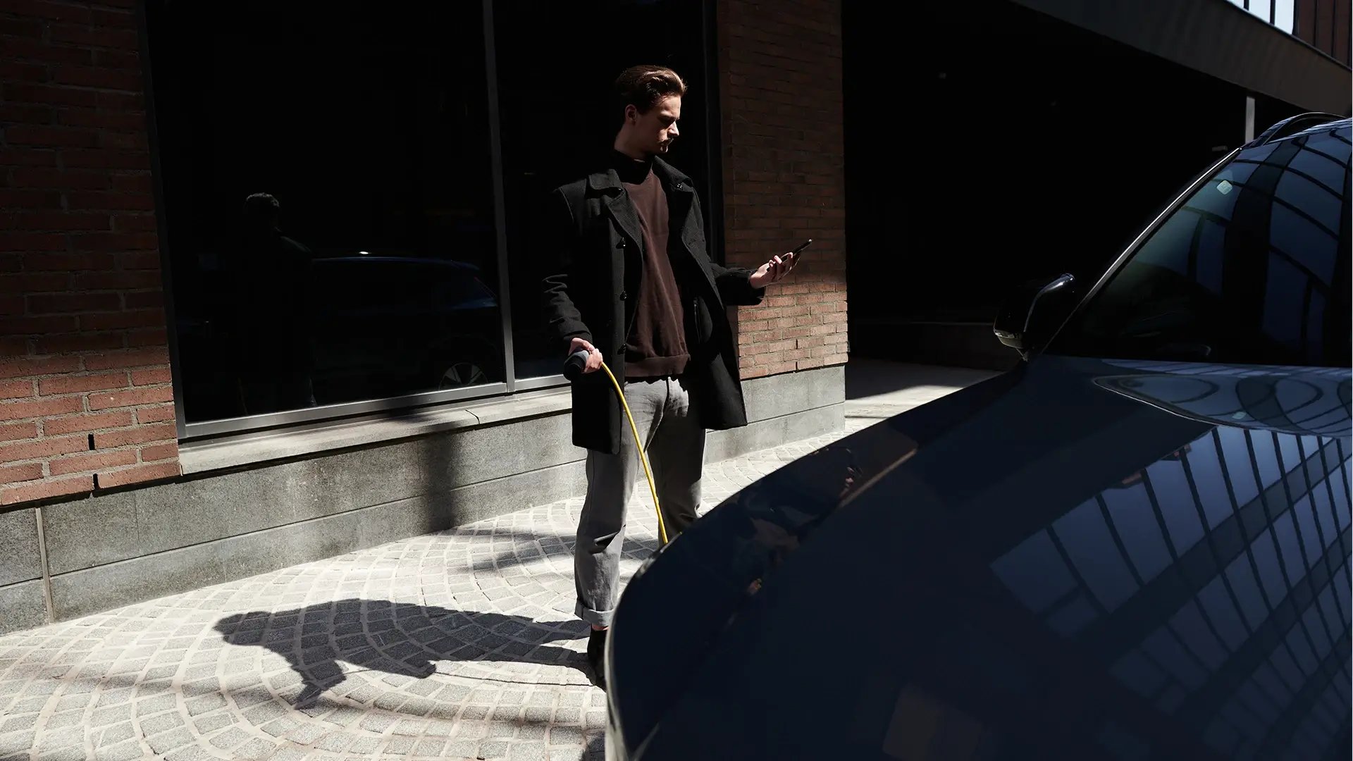 Businessman using EV charging station smartphone in hand