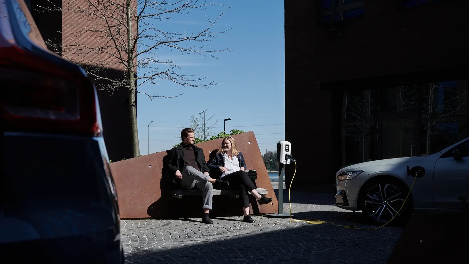 Paar sitzt neben einer Virta AC Ladestation