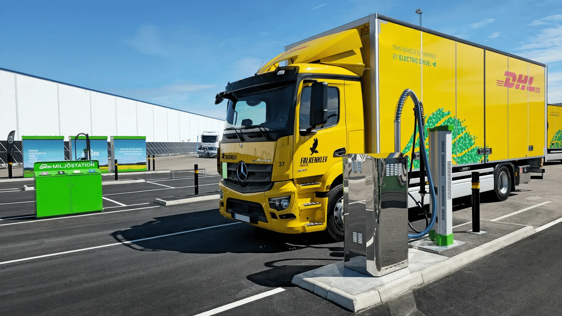 En DHL-lastbil som laddas bredvid en snabb DC-laddare från Rifil med blå himmel i bakgrunden