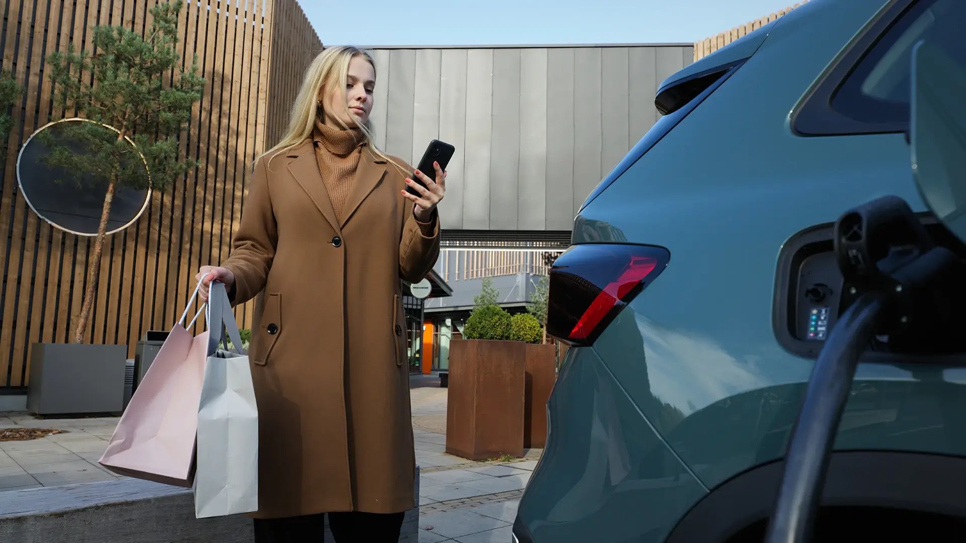 Kvinde styrer opladningsapp, mens hun oplader elbil