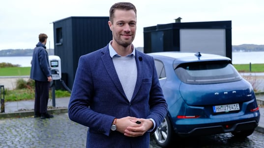 Man beside electric vehicle and AC charging station