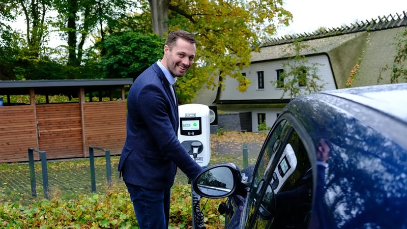 Man standing beside EV and AC charger