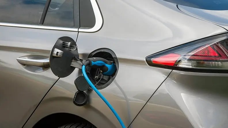 sand colored car being recharged with blue cable