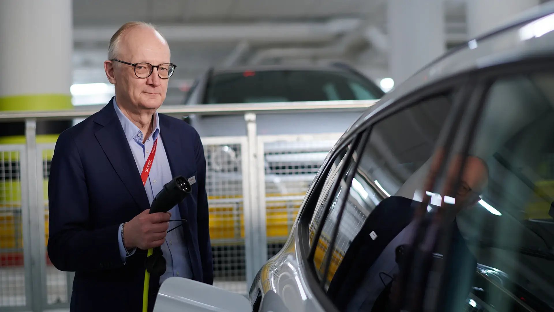 Geschäftsführer von Scandic Hotel in Turku hält Ladekabel an E-Auto in Hotel Tiefgarage
