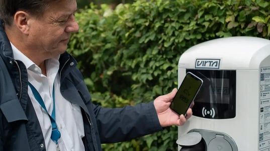 Man beside AC charger with smartphone charging app