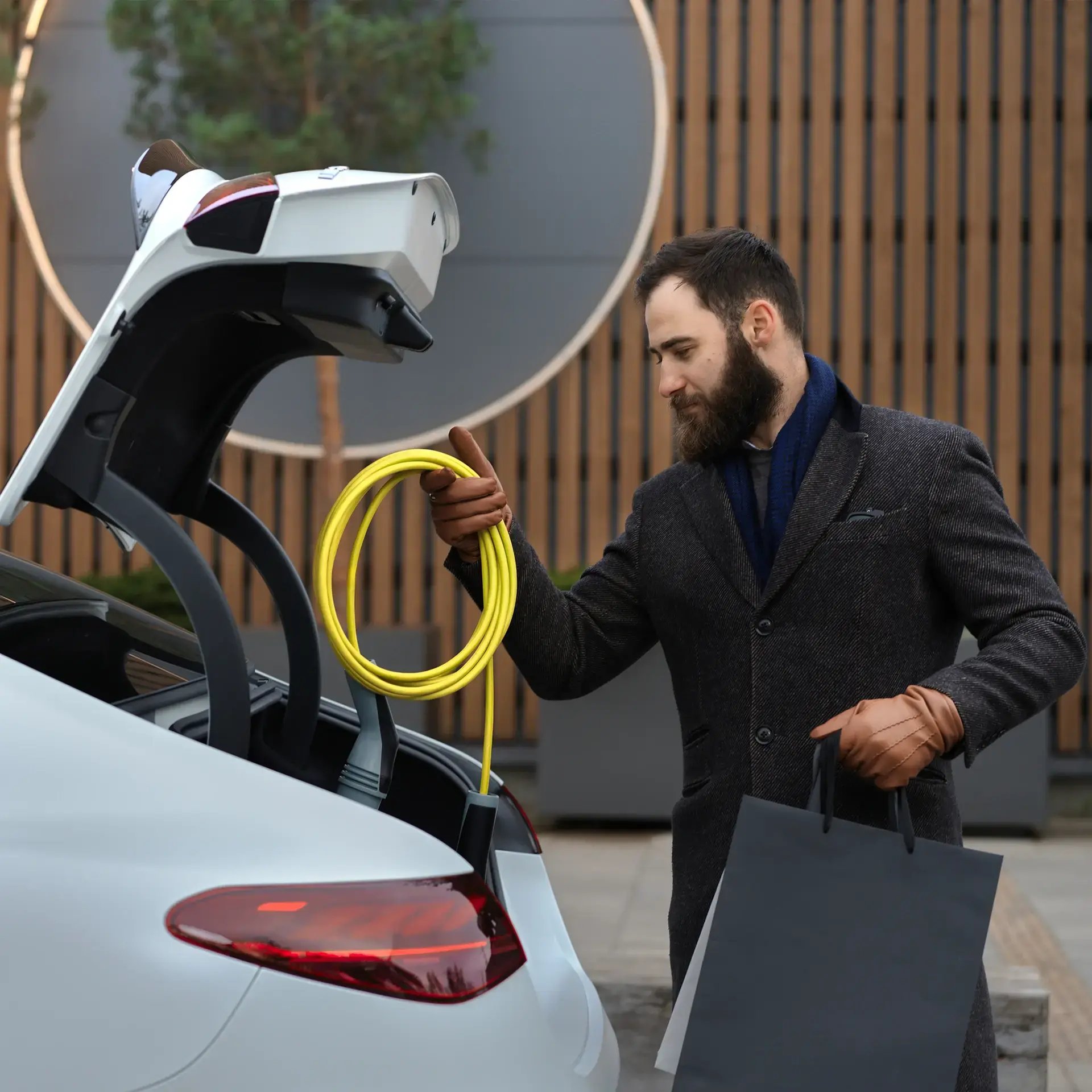 Man putting EV charging cable in EV trunk