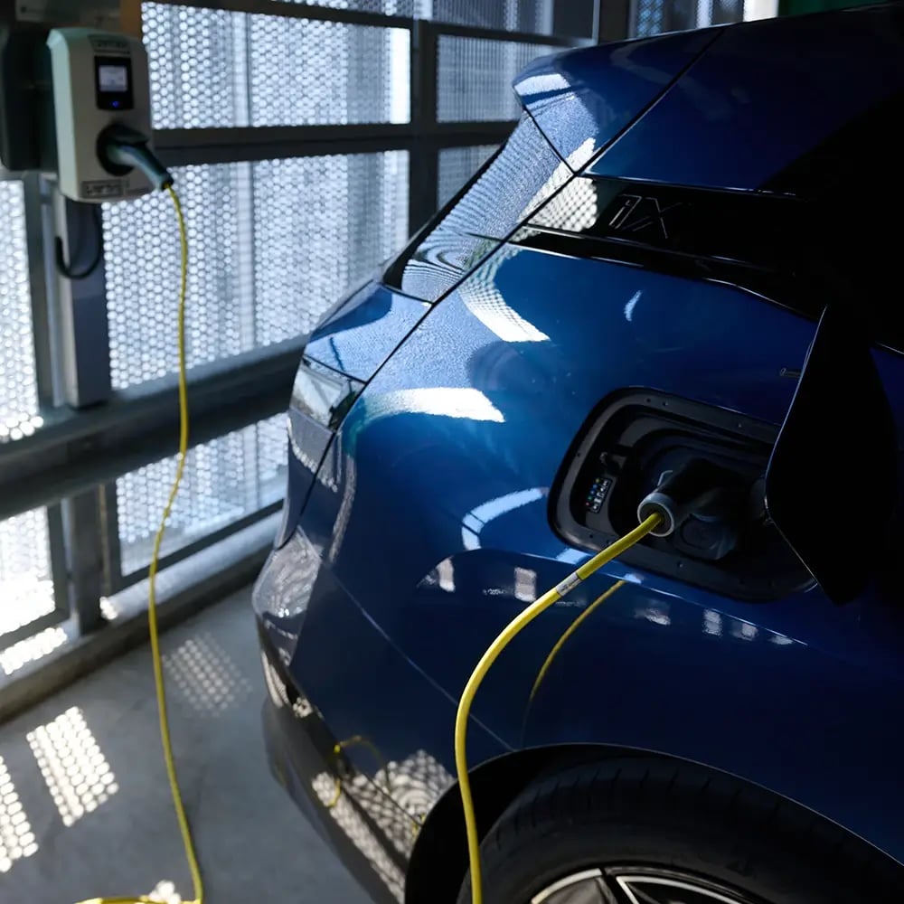 Véhicule électrique dans un parking municipal, connecté à une station de recharge AC
