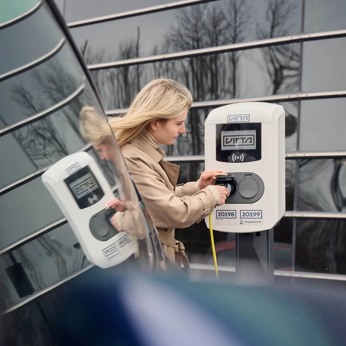 Woman charging an EV beside an AC charging station