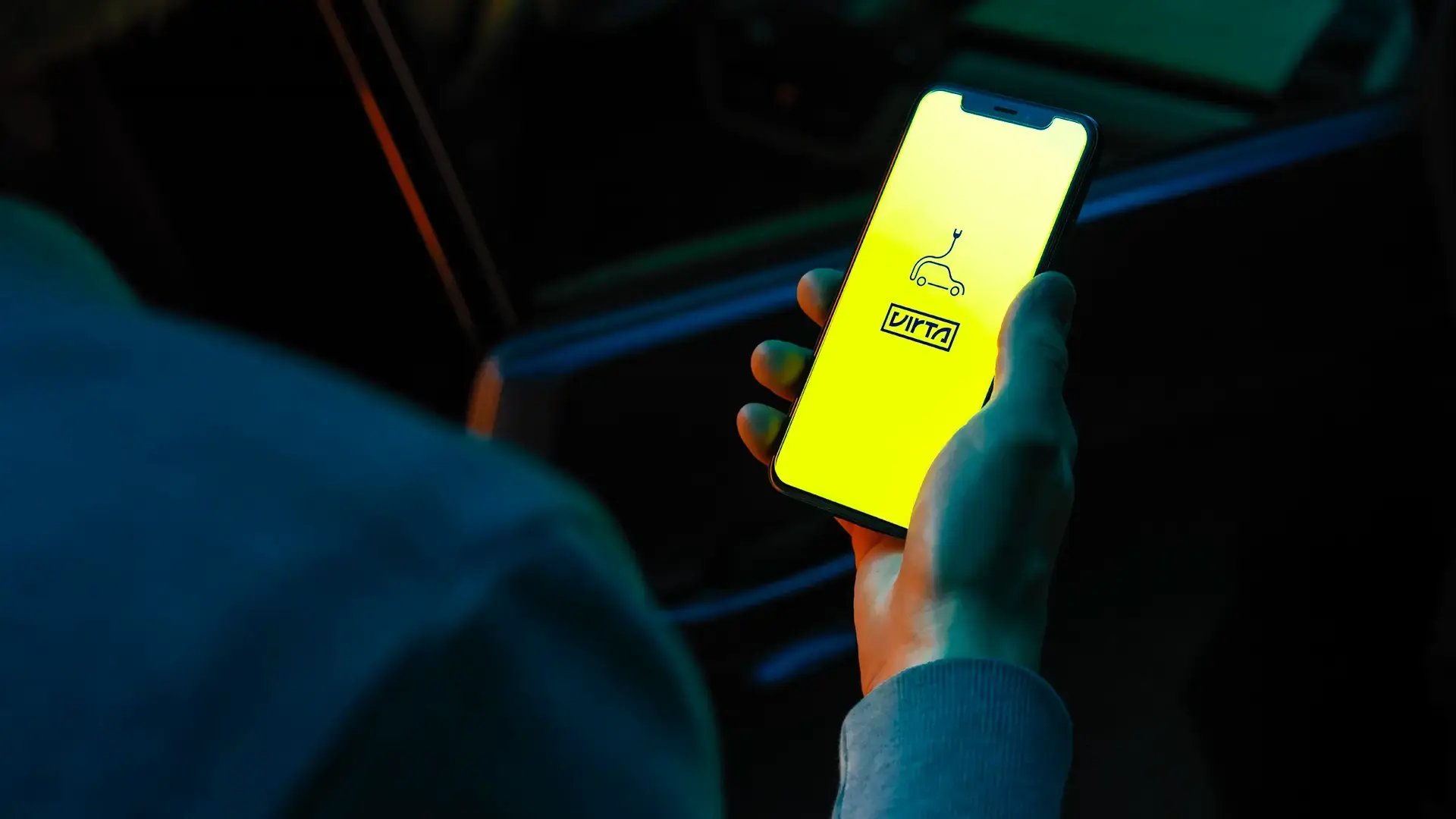 Hand holding mobile phone with Virta yellow app