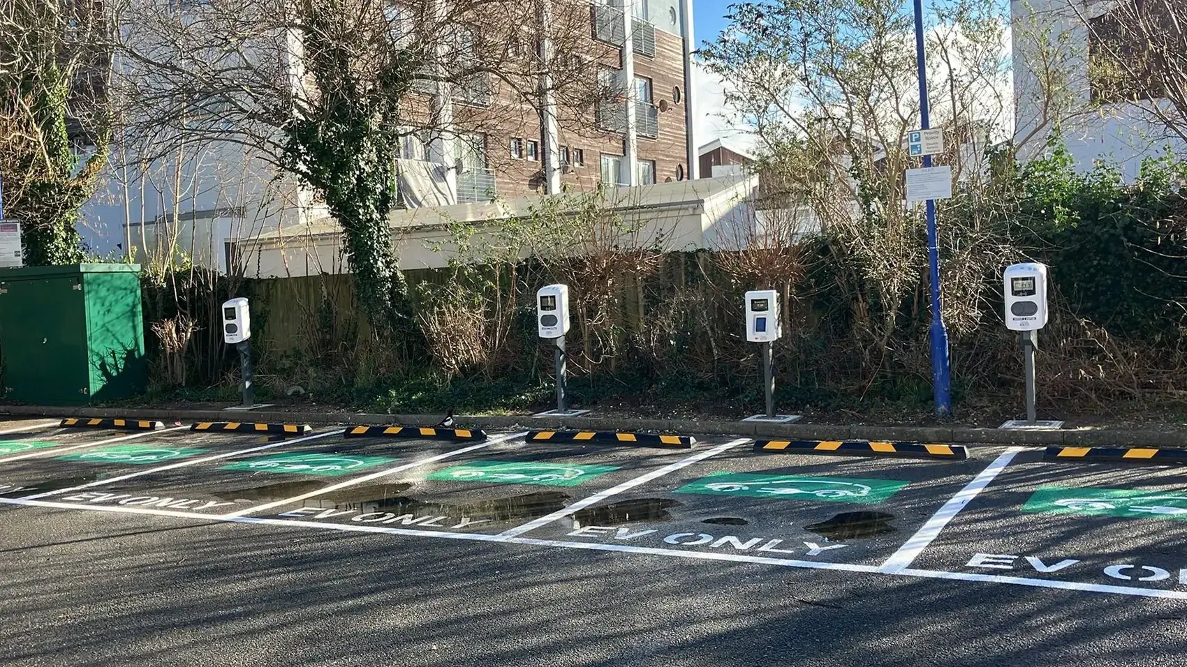 Row of AC chargers and a Payment Kiosk at a parking lot marked for electric vehicle charging